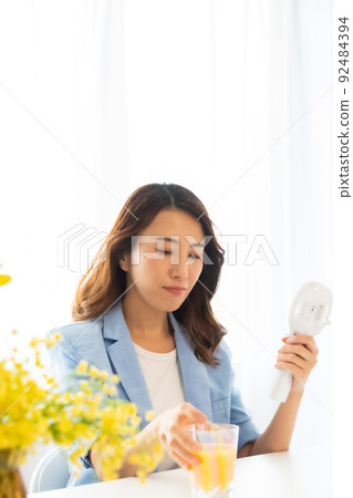 一個用電風扇尋求涼爽的女人 92484394
