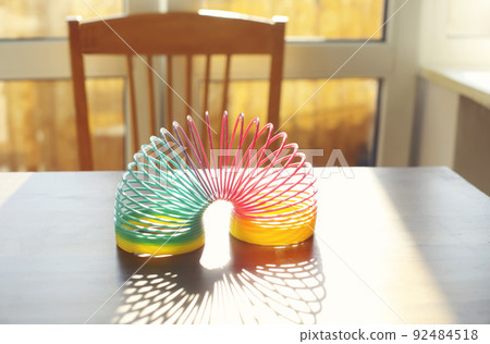 Anti-stress magic rainbow ring spring on table in sunny room Anti-stress magic rainbow ring spring on table in sunny room 92484518