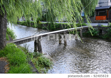 A row of willow trees in Shirakawa, Kyoto City crosses the cool Gyojabashi Bridge 92485619