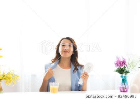 一個用電風扇尋求涼爽的女人 92486995