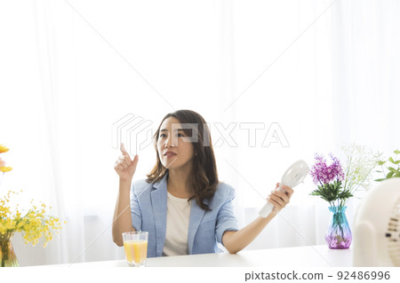 A woman seeking coolness with an electric fan 92486996