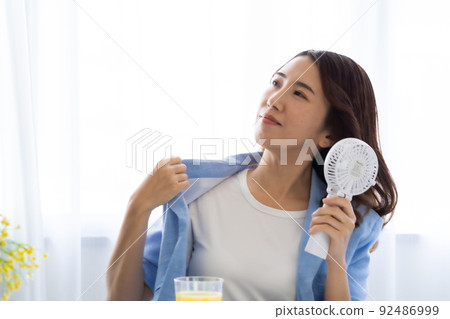 一個用電風扇尋求涼爽的女人 92486999