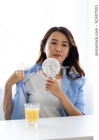 一個用電風扇尋求涼爽的女人 92487001