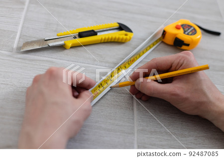 Man hands measuring decorative plastic corner. Repairing at home. 92487085