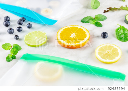 Food storage bags with fruit and vegetables, on a white marble kitchen table Food storage bags with fruit and vegetables, on a white marble kitchen table 92487394