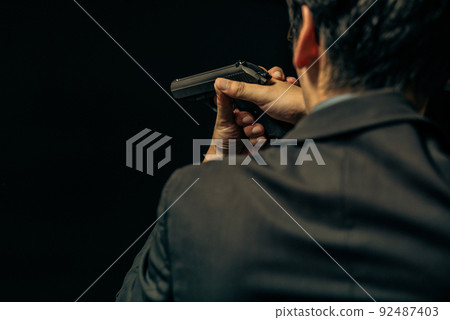 A person in a suit holding a pistol 92487403