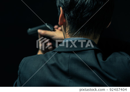A person in a suit holding a pistol 92487404