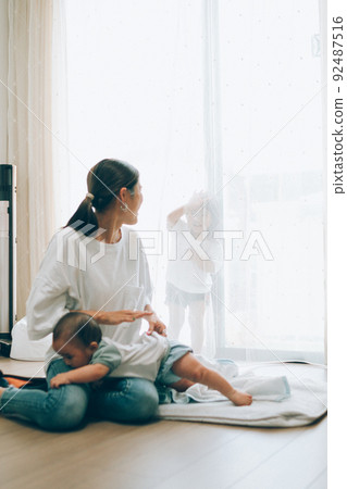 A mother playing with her daughter while taking care of her son 92487516