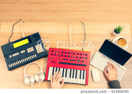 top view of professional music producer, composer hands arranging music on computer and recording equipments on desk. music production technology, home studio top view of professional music producer, composer hands arranging music on computer and recording equipments on desk. music production technology, home studio 92488040