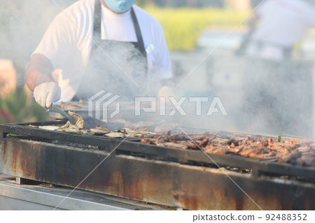 Cook prepares fish and meat on grill in market or cafe Cook prepares fish and meat on grill in market or cafe 92488352