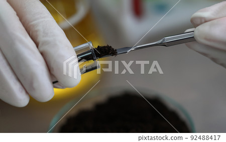 Researcher holds glass flask with earth in hand 92488417