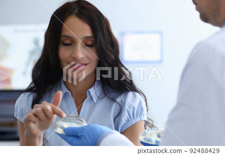 Woman touching breast implants talking to plastic surgeon Woman touching breast implants talking to plastic surgeon 92488429