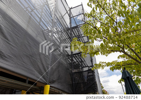 A 25-year-old single-family house with scaffolding for roof and exterior wall remodeling work 92488714