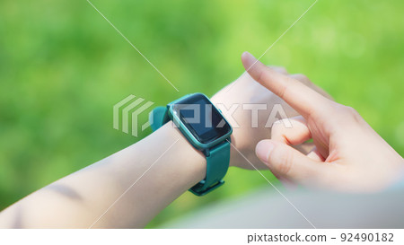 A woman using a smartwatch outdoors A woman using a smartwatch outdoors 92490182