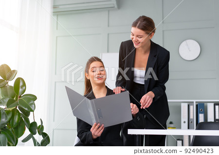 Young women leaders are checking financial statements from paper documents. Two female confident business worker dressed black suit in office checking financial document 92490423