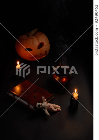 Halloween pumpkin with burning mouths, book and a voodoo doll - volt on dark background. Halloween pumpkin with burning mouths, book and a voodoo doll - volt on dark background. 92490452