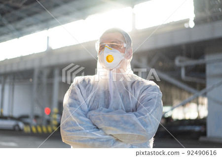 COVID-19 coronavirus doctor standing hospital parking dressed white protective overalls hazmat suit. COVID-19 coronavirus doctor standing hospital parking dressed white protective overalls hazmat suit. 92490616