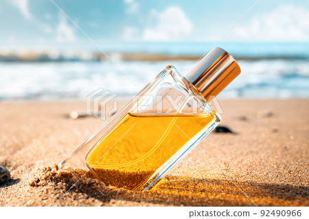 A bottle of perfume on the sandy shore of the ocean. Style perfumery template A bottle of perfume on the sandy shore of the ocean. Style perfumery template 92490966