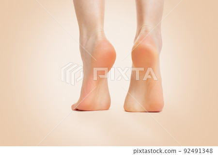 Beautiful female feet, with smooth and soft heels, close-up on a beige background. Copy space. Back view. Concept of cosmetology, dermatology and health 92491348