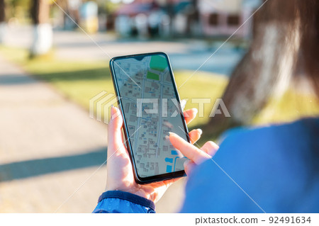 A woman uses an application with an online navigator in her smartphone. Close-up of the hand of the device screen. Concept of intenet navigation A woman uses an application with an online navigator in her smartphone. Close-up of the hand of the device screen. Concept of intenet navigation 92491634