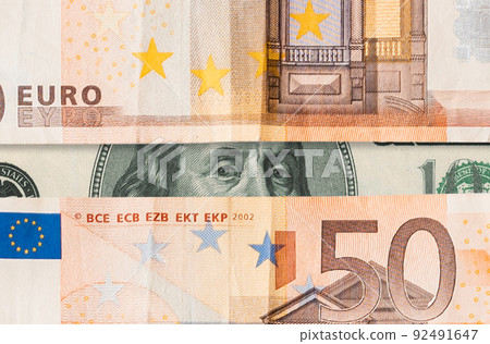 Stock exchange. Dollar and euro banknotes, close-up. Benjamin Franklin's sight between paper currency, horizontal opening. Flat lay. The concept of the global crisis, investment and trading Stock exchange. Dollar and euro banknotes, close-up. Benjamin Franklin's sight between paper currency, horizontal opening. Flat lay. The concept of the global crisis, investment and trading 92491647