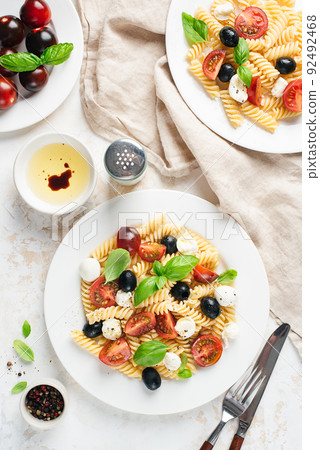 Italian pasta with tomatoes, mozzarella cheese and black olives Italian pasta with tomatoes, mozzarella cheese and black olives 92492468