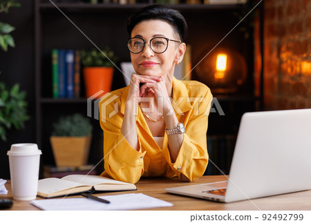 Stylish businesswoman taking break in work and looking at camera Stylish businesswoman taking break in work and looking at camera 92492799