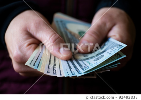 White male shows dollar bills in his hand closeup front view 92492835