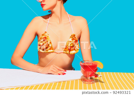 Cropped image of female body, cocktail on yellow tablecloth and pizza element on cloth isolated on blue background 92493321