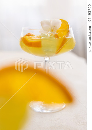 Transparent cocktail with ice cubes in a glass decorated with slices of orange close up 92493700