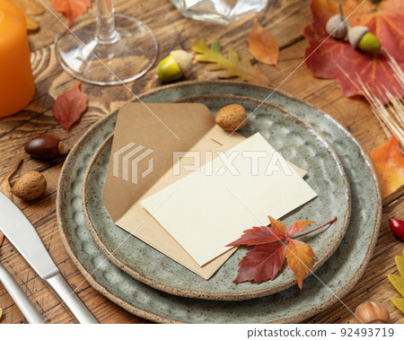 Autumn table setting with place card and envelope between leaves and berries close up, mockup 92493719