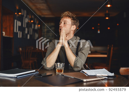 Man drinks whiskey. Businessman reads documents. Director in a shirt and suspenders. Man drinks whiskey. Businessman reads documents. Director in a shirt and suspenders. 92493879