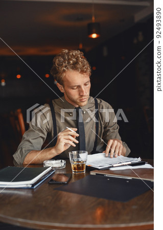 Man drinks whiskey. Businessman reads documents. Director in a shirt and suspenders. Man drinks whiskey. Businessman reads documents. Director in a shirt and suspenders. 92493890
