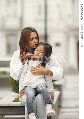 Family near the city fountain. Mother with gaughter playing with water. 92493924