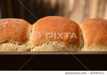 Food composition. Cropped view of a freshly baked hot whole grain bread,on a wooden background with copy ad space Food composition. Cropped view of a freshly baked hot whole grain bread,on a wooden background with copy ad space 92494317