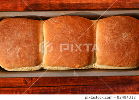Flat lay. Food composition of a freshly baked hot whole grain bread,on a wooden background with copy ad space Flat lay. Food composition of a freshly baked hot whole grain bread,on a wooden background with copy ad space 92494318