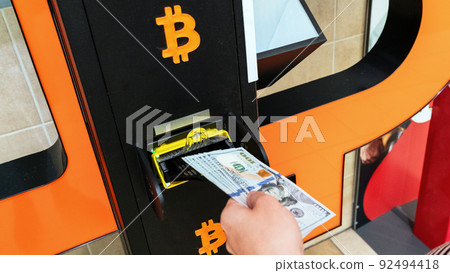 Atm machine bitcoin cryptocurrency. Usd hundred money payment on virtual crypto currency btc wallet. Woman withdraw american dollar bill money. Atm machine finance and technology concept. 92494418