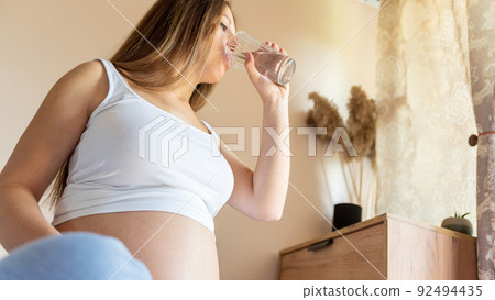 Pregnant drink water. Beautiful pregnancy drinking water. Happy pregnant lady holding glass of water. Pregnancy, maternity, healthcare concept. Pregnant drink water. Beautiful pregnancy drinking water. Happy pregnant lady holding glass of water. Pregnancy, maternity, healthcare concept. 92494435