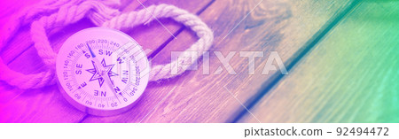 Compass and rope on wooden texture background in neon light Compass and rope on wooden texture background in neon light 92494472