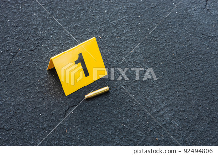 One yellow crime scene evidence marker on the street after a gun shooting brass bullet shell casing rifle 92494806