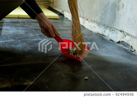 Worker sweeps construction debris with a broom. Worker sweeps construction debris with a broom. 92494936
