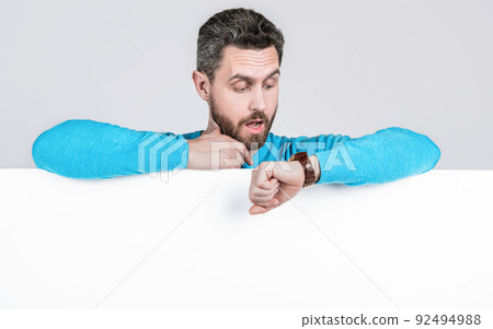 shocked man checking time behind blank white paper banner with copy space for ad, shopping sale time shocked man checking time behind blank white paper banner with copy space for ad, shopping sale time 92494988