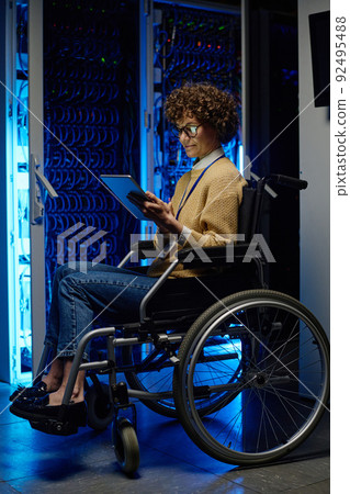 Female system admin with disability using computer while setting up server network Female system admin with disability using computer while setting up server network 92495488