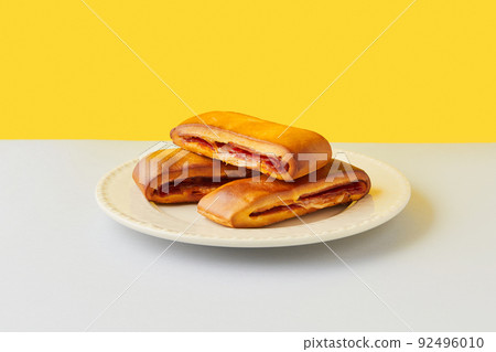 Lanche misto traditional portuguese sandwich with cheese and chorizo. Tasty breakfast over yellow background. 92496010