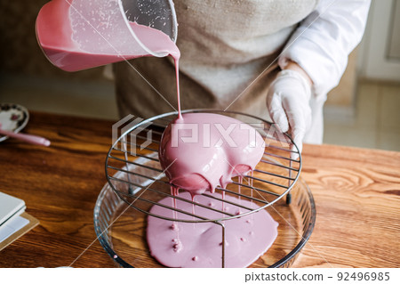 Mousse heart shape pink cake in hand of Asian Arabic woman pastry chef. Mirror Glaze Cake. Process Mousse heart shape pink cake in hand of Asian Arabic woman pastry chef. Mirror Glaze Cake. Process 92496985