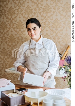 Female baker, pastry chef preparing cake order. Arabic Asian woman making cake for online delivery 92496986