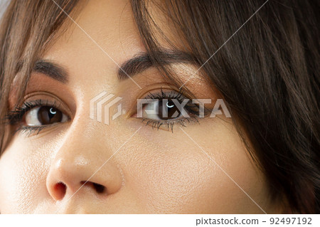 Glamour close-up portrait of beautiful woman model face with winged black eyeliner make-up, clean skin on white background. Long eyelashes and thick eyebrows. Glamour close-up portrait of beautiful woman model face with winged black eyeliner make-up, clean skin on white background. Long eyelashes and thick eyebrows. 92497192