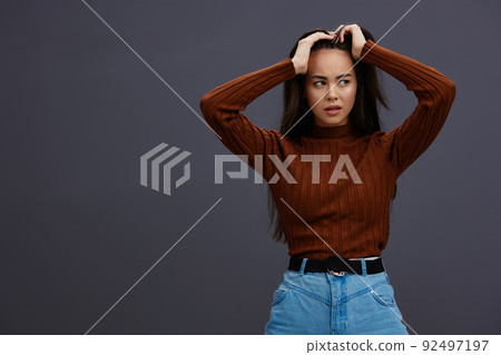 young woman hand gestures brown sweater fashion emotions Gray background young woman hand gestures brown sweater fashion emotions Gray background 92497197