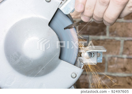 Knife sharpener and hand with blade on wooden table, closeup 92497605