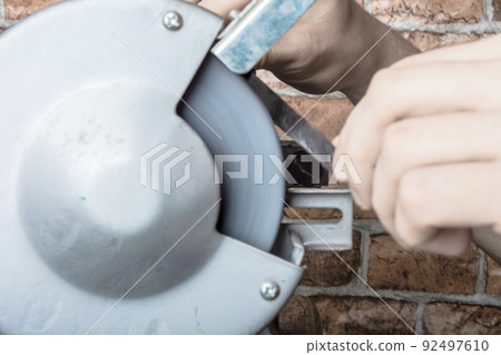 Knife sharpener and hand with blade on table, closeup Knife sharpener and hand with blade on table, closeup 92497610